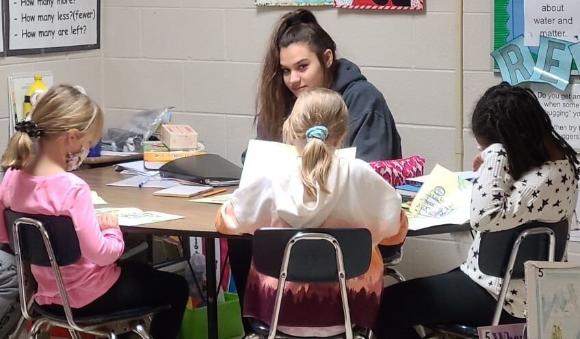 Older student teaching younger students to read.