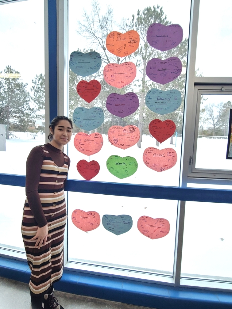 HS student standing by window covered in hearts.