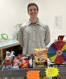 Student standing in front of the school store cart, which contains snacks that are for sale.