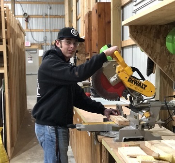 Student using saw to cut a piece of lumber.