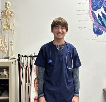 Health Science student standing by a skeleton.